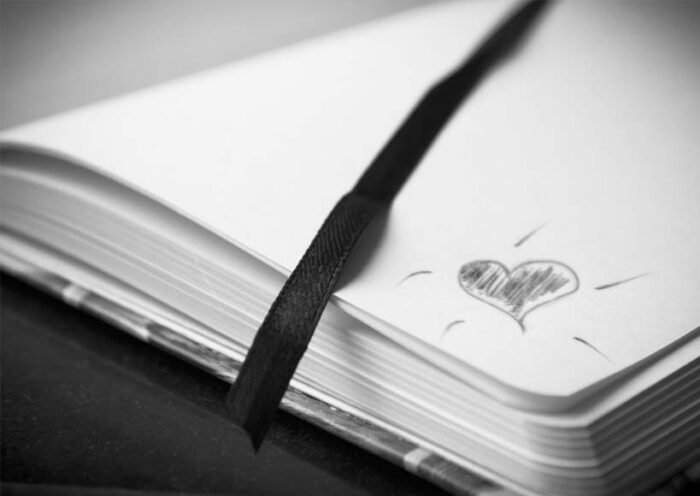 Open notebook with a black ribbon bookmark and a hand drawn heart on the page
