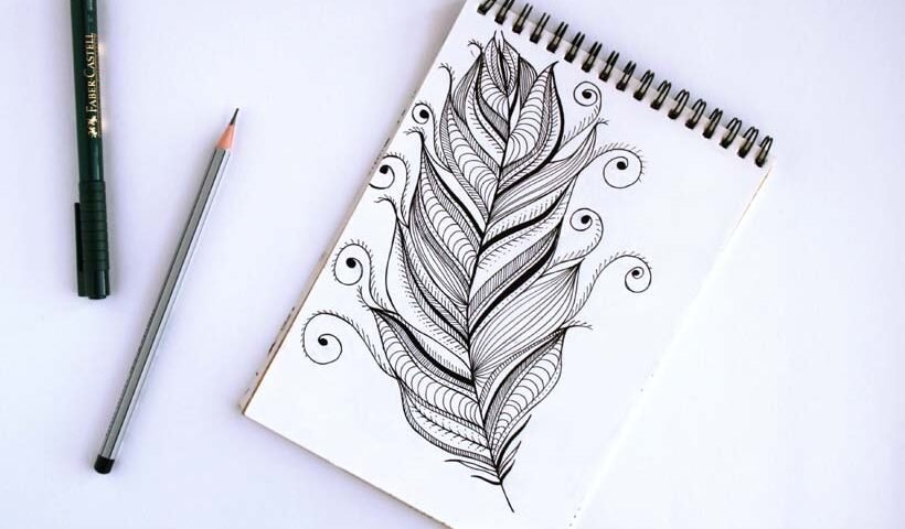 Notebook with a detailed black ink feather/leaf doodle, a pencil and black marker on a white surface
