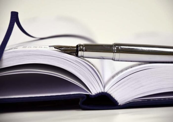 Open hardcover notebook with a silver fountain pen resting on its pages ready for writing or note taking