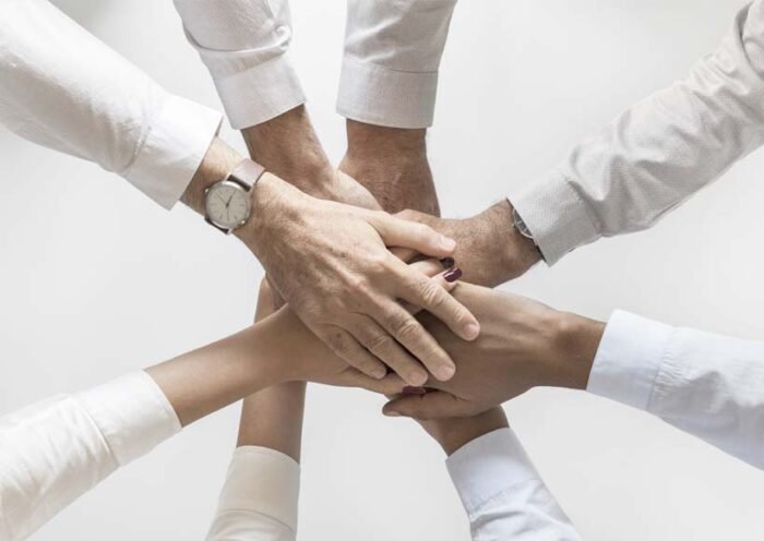 Six hands stacked together in a circle symbolizing teamwork and collaboration