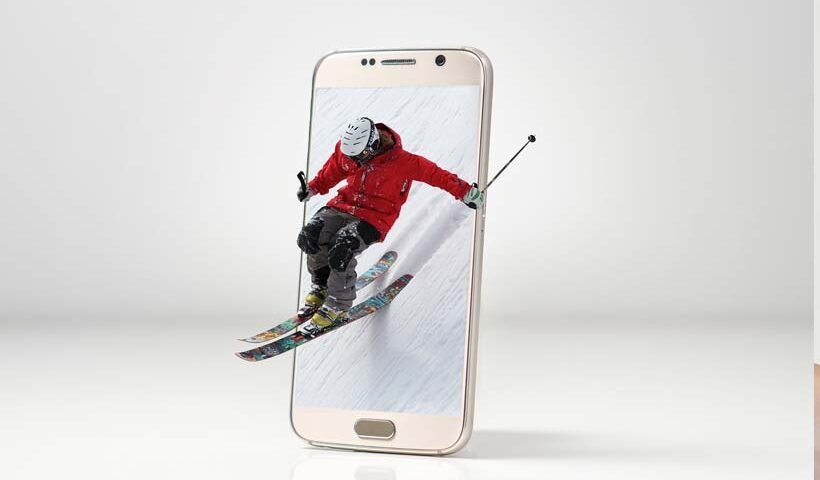Skier in a red jacket jumps through a smartphone screen, as if the phone is a portal to action.