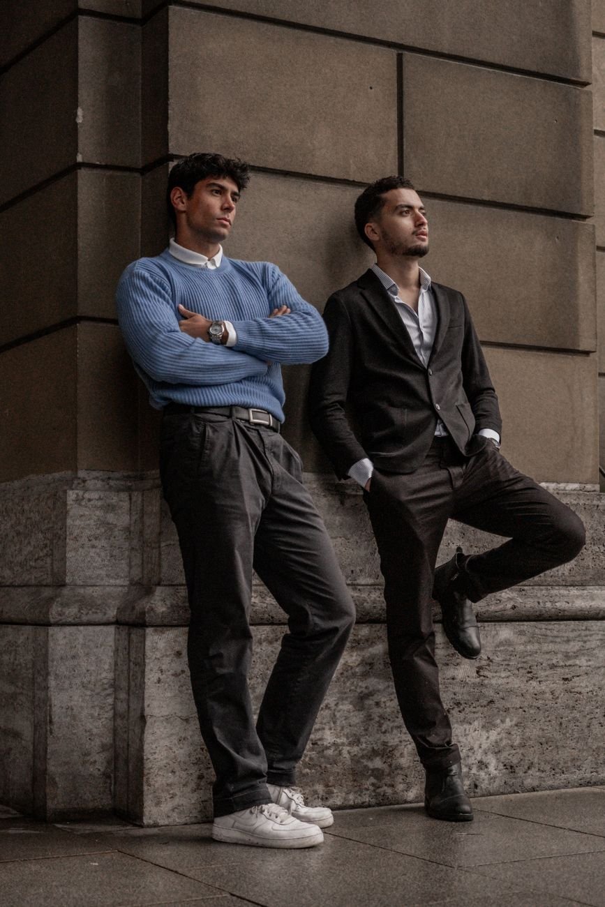 stylish urban fashion duo leaning wall outdoors