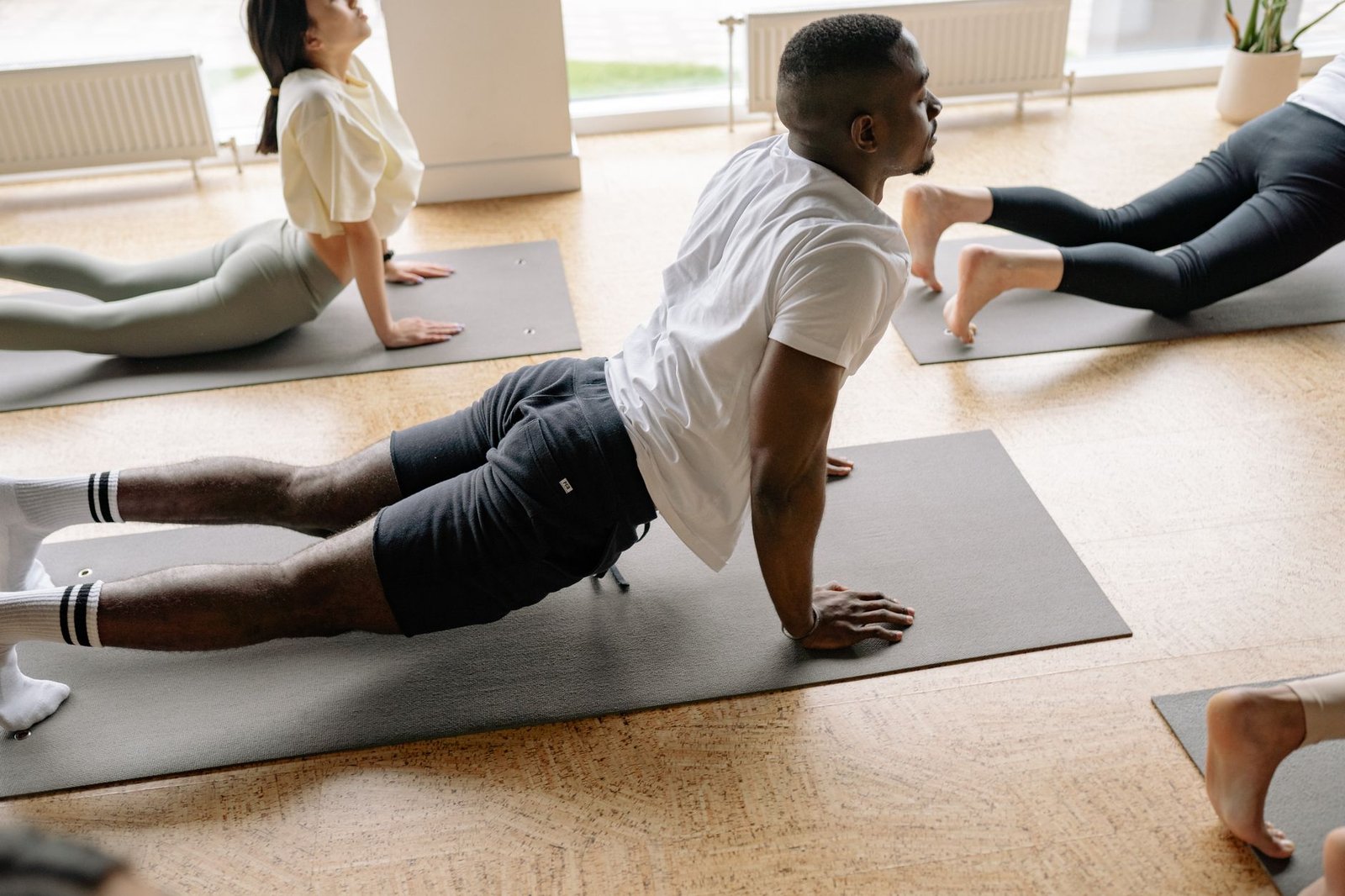 man in white t shirt and black shorts doing stretching on floor